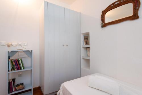 a white bedroom with a bed and a mirror at Stunning Sunset House on Kamares Bay with Playground in Kamarai