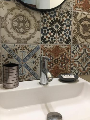 a bathroom sink with a faucet and tiles at happyWish Syros in Ermoupoli
