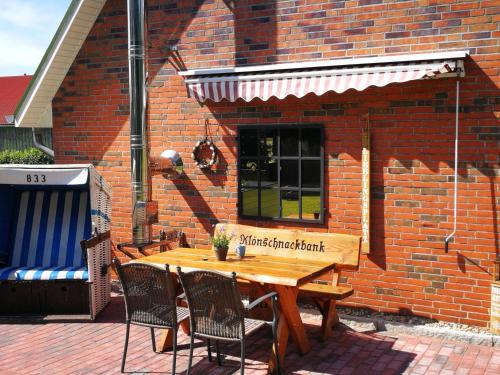 a wooden table and chairs in front of a brick building at Gästehaus Nord-West 1700 - Einzelzimmer "Düne" in Steenfeld
