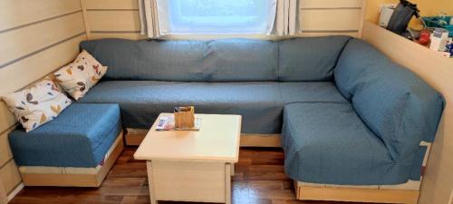 - un canapé bleu dans une petite chambre avec une table dans l'établissement MOBIL HOME 43 dans Camping 4 Etoiles, à Gastes