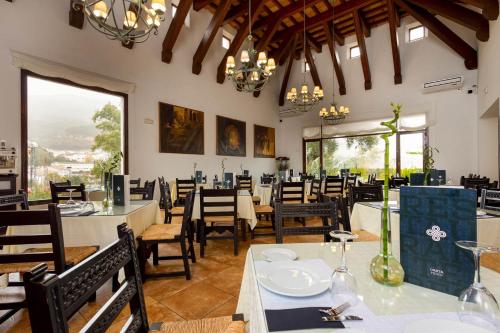 un comedor con mesas, sillas y ventanas en Hotel Tugasa Las Truchas, en El Bosque