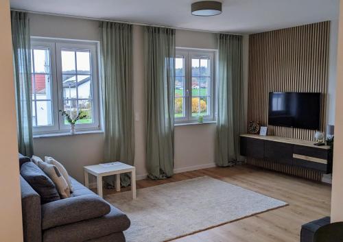 een woonkamer met een bank en een flatscreen-tv bij Inheidener Neubau Ferienwohnung in Hungen
