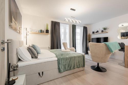 a white bedroom with a bed and a chair at Heroes Square Apartment in Budapest