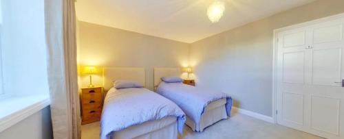 two beds in a bedroom with white walls at North Lodge in Cheltenham