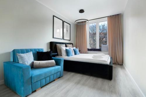 a bedroom with a bed and a blue chair at Elite Apartments Garncarska Classy in Gdańsk