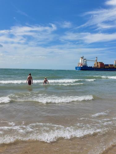 two people in the ocean with a ship in the background at Strandcamping Valkenisse in Biggekerke