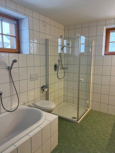 La salle de bains est pourvue d'une douche, de toilettes et d'une baignoire. dans l'établissement Walserklause Ferienwohnung, à Raggal