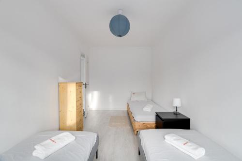 Duas camas num quarto com paredes brancas em Hopstays - Almada Getaway em Almada