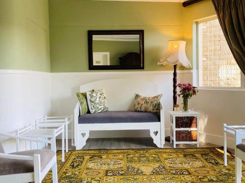 Karoo Country Guesthouse في De Aar: غرفة معيشة مع مقعد ومرآة