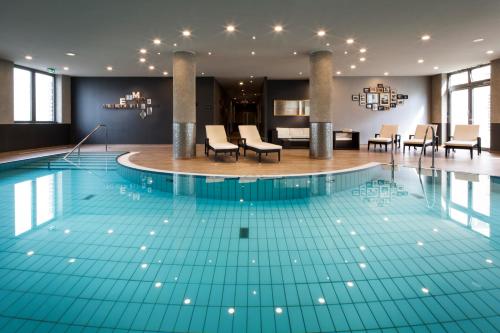 a pool in a hotel with chairs and tables at Pentahotel Leipzig in Leipzig