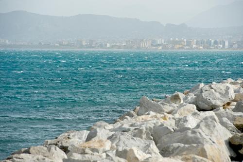 a group of rocks by the ocean with a city at Mercure Palermo Centro in Palermo