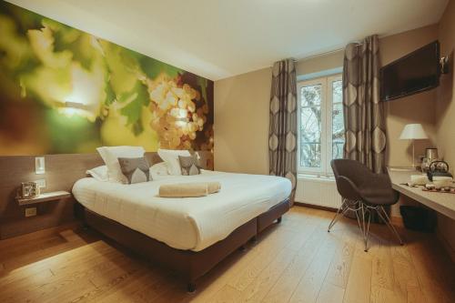 a bedroom with a bed with a painting on the wall at Auberge de Clochemerle, Spa privatif & restaurant gastronomique in Vaux-en-Beaujolais