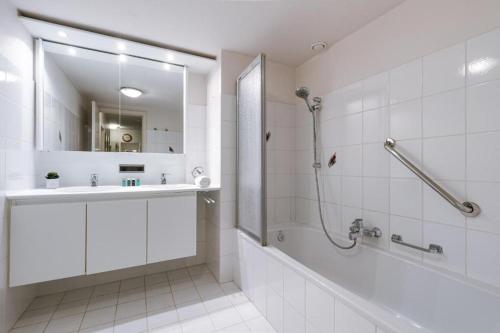 een witte badkamer met een douche, een bad en een wastafel bij Apartment Alios in Oostende