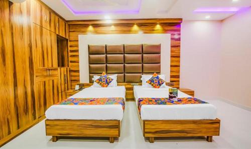 two beds in a bedroom with wooden walls at FabHotel Prime Orion Crystal in Kolkata