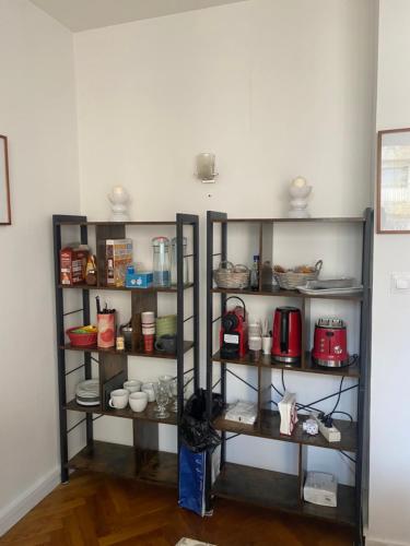 une étagère avec des tasses, des casseroles et des poêles dans l'établissement Neuilly-sur-Seine calme et lumineux. B&B. 3 chambres, à Neuilly-sur-Seine