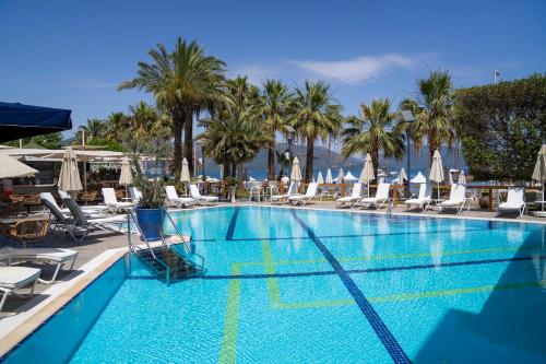 a large swimming pool with chairs and palm trees at Cettia Beach Resort in Marmaris