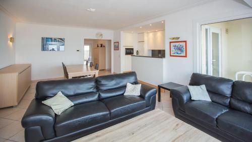 salon z czarną skórzaną kanapą i kuchnią w obiekcie Bright Apartment With Sea View w Ostendzie