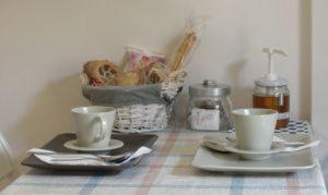 a table with two cups and a basket of bread at La Casa delle Betulle in Cardano al Campo