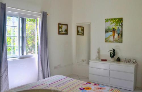 um quarto com uma cama, uma janela e uma cómoda em Stunning Villa overlooking Friendship Bay Beach em Union