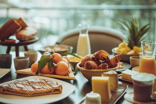 Una mesa cubierta con platos de desayuno y jugo de naranja. en Auberge de Clochemerle - Spa & Restaurant gastronomique étoilé, en Vaux-en-Beaujolais