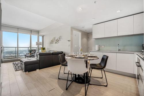 a kitchen and living room with a table and a couch at NEW! 34th FL High Rise, PRIME Location, Downtown Near Stampede & Saddledome, FREE Wine & More! in Calgary