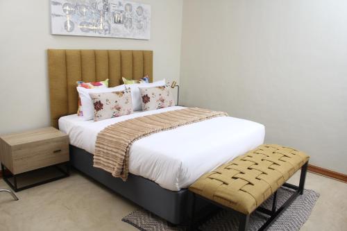 Un dormitorio con una cama con sábanas y almohadas blancas. en The Oak Tree House, en Gaborone