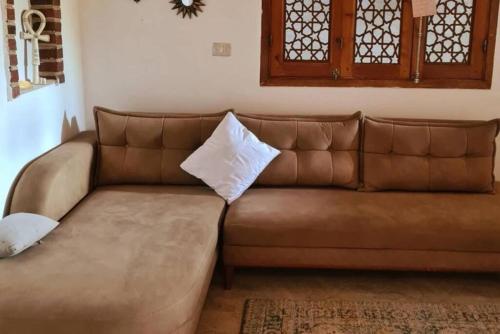 a brown leather couch with a white pillow on it at El Hanna Valley View in Luxor