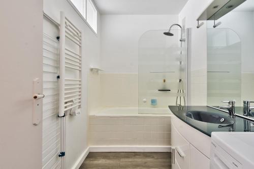 une salle de bain avec un lavabo et une baignoire dans l'établissement Aux portes de l'océan à Saint-Jean-de-Monts, à Saint-Jean-de-Monts
