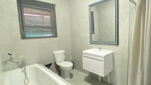 a white bathroom with a tub and a toilet and a sink at Ubuhle Guest House in Standerton