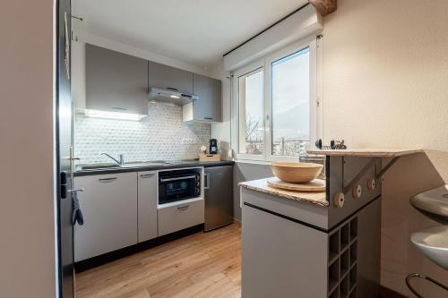 une cuisine avec des armoires blanches, un évier et une fenêtre dans l'établissement Les Cèdres Bleus, à Albertville