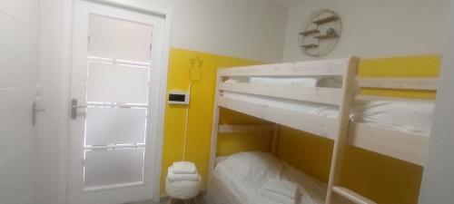 Cette petite chambre comprend 2 lits superposés et une porte. dans l'établissement La rose des vents, à Wimereux