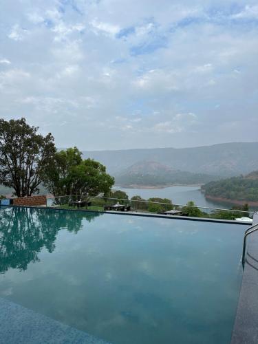 a swimming pool with a view of a lake at Nisarga Lake Resort in Satara