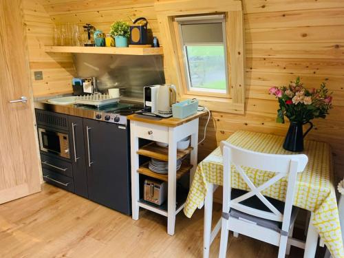 a kitchen with a stove and a table with chairs at The Pod Over By in Kilmichael Glassary
