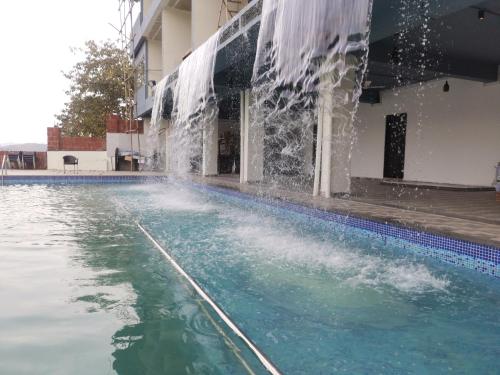 a swimming pool with a water fountain at Nisarga Lake Resort in Satara