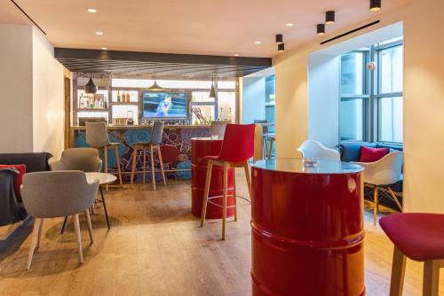 a restaurant with red chairs and a bar at Ibis Casablanca Sidi Maarouf in Casablanca
