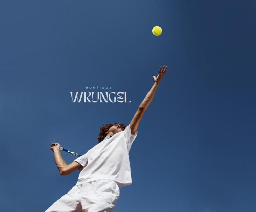 Un uomo che colpisce una palla da tennis con una racchetta di Boutique Wrungel a Vrsar