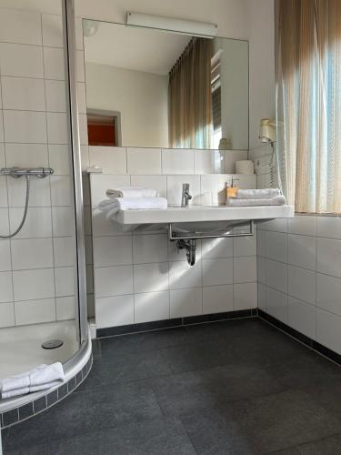 La salle de bains est pourvue d'un lavabo et d'un miroir. dans l'établissement Hotel-Restaurant Schraeder, à Greven