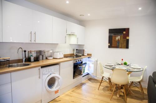 uma cozinha com uma máquina de lavar roupa e uma mesa com cadeiras em Luxury 2 Bed Apartment em Manchester