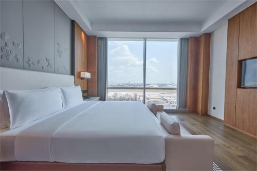 a large white bed in a room with a large window at VM Hotel in Phnom Penh
