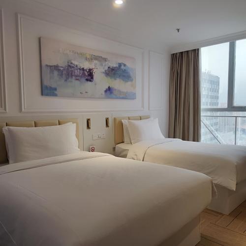 two beds in a hotel room with a window at Magnificent International Hotel in Shanghai