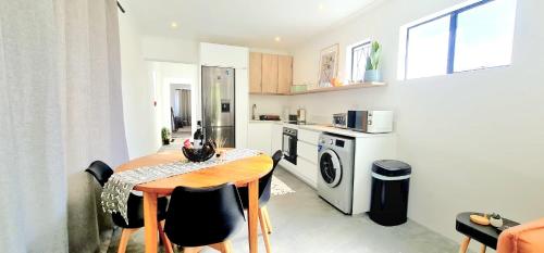 uma cozinha com uma mesa de madeira e cadeiras num quarto em Private 2 Bed Guest Suite with Garden em Cidade do Cabo