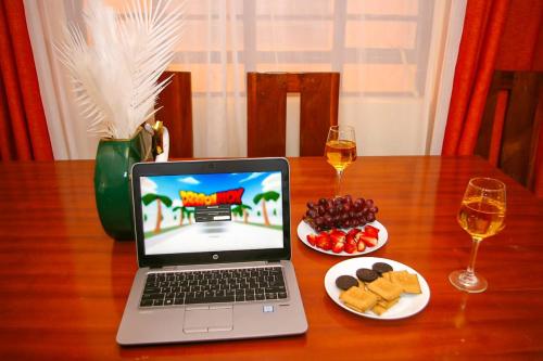 un ordenador portátil sentado en una mesa de madera con comida y vino en Forest Cabins en Nyeri