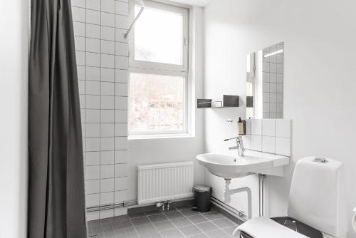 een witte badkamer met een wastafel en een raam bij Gibsons Hotell in Jonsered