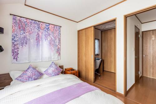 a bedroom with a bed and a painting on the wall at Charming New Home Launch: Direct access to Narita & Haneda Airports, Shinjuku, and Disneyland; Close to Asakusa & Akihabara! in Tokyo