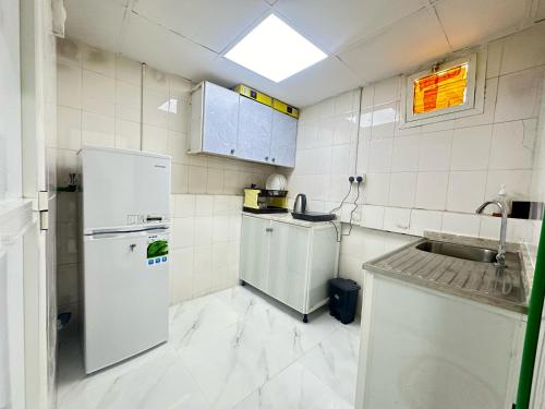 a small kitchen with a refrigerator and a sink at Comfy Studio Apartment in Abu Dhabi