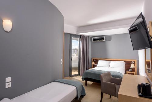 a hotel room with two beds and a desk and a tv at Iraklion Hotel in Heraklio Town