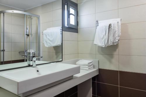 a bathroom with a sink and a mirror and towels at Iraklion Hotel in Heraklio Town