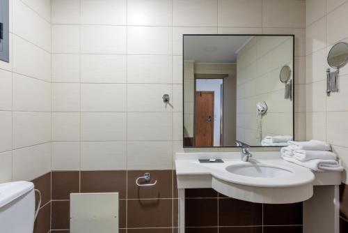 a bathroom with a sink and a mirror and a toilet at Iraklion Hotel in Heraklio Town