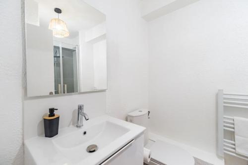 La salle de bains blanche est pourvue d'un lavabo et de toilettes. dans l'établissement Studio le charme Breton - Saint-Brieuc, à Saint-Brieuc