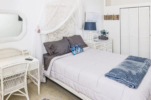 ein weißes Schlafzimmer mit einem Bett und einem Stuhl in der Unterkunft Annes Revenge The Bonney Overlook in Christiansted